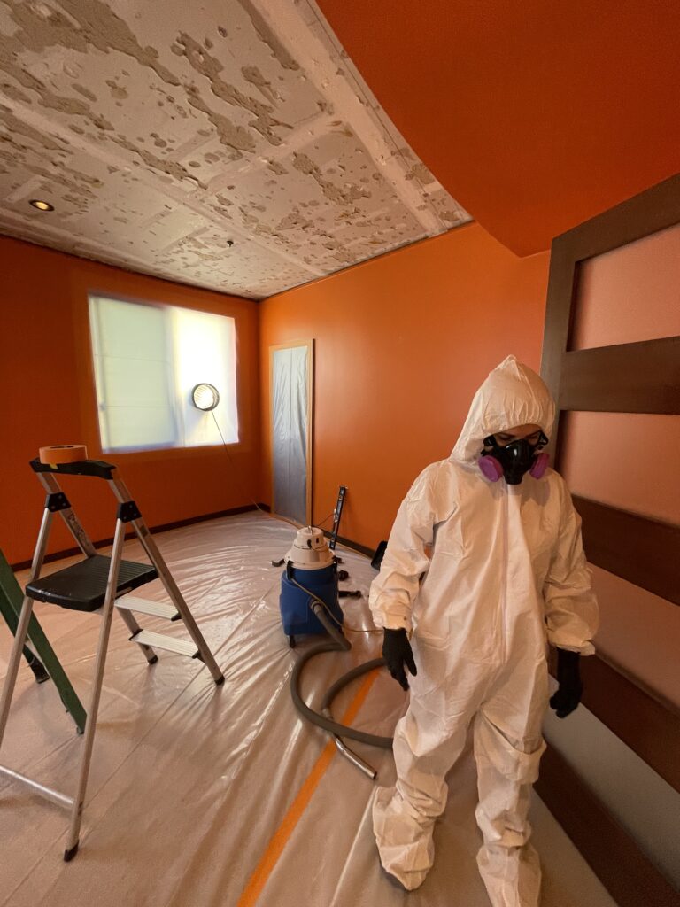 a person in a white suit and mask removing mold in an orange county home