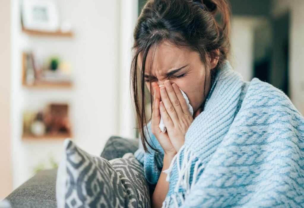 a woman blowing her nose and experiencing mold symptoms and allergies